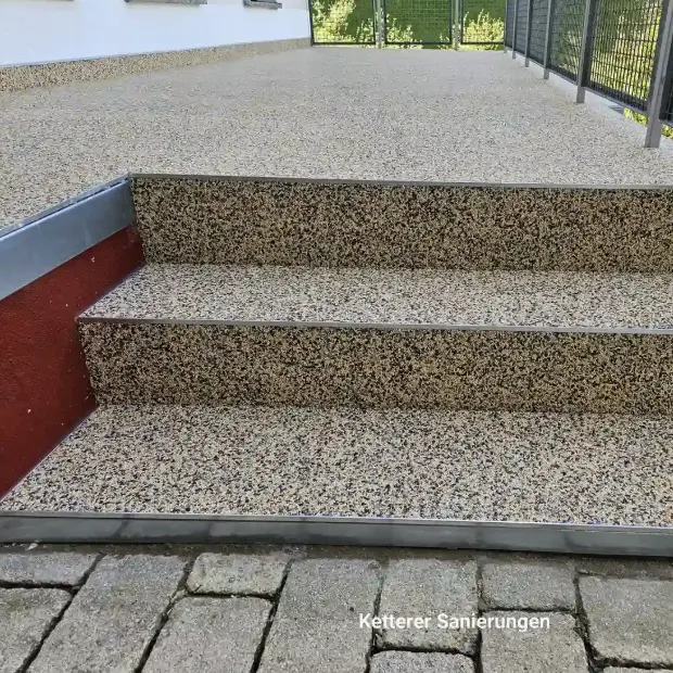 Eine dreistufige, frisch sanierte Treppe als Zugang zu einer Terrasse